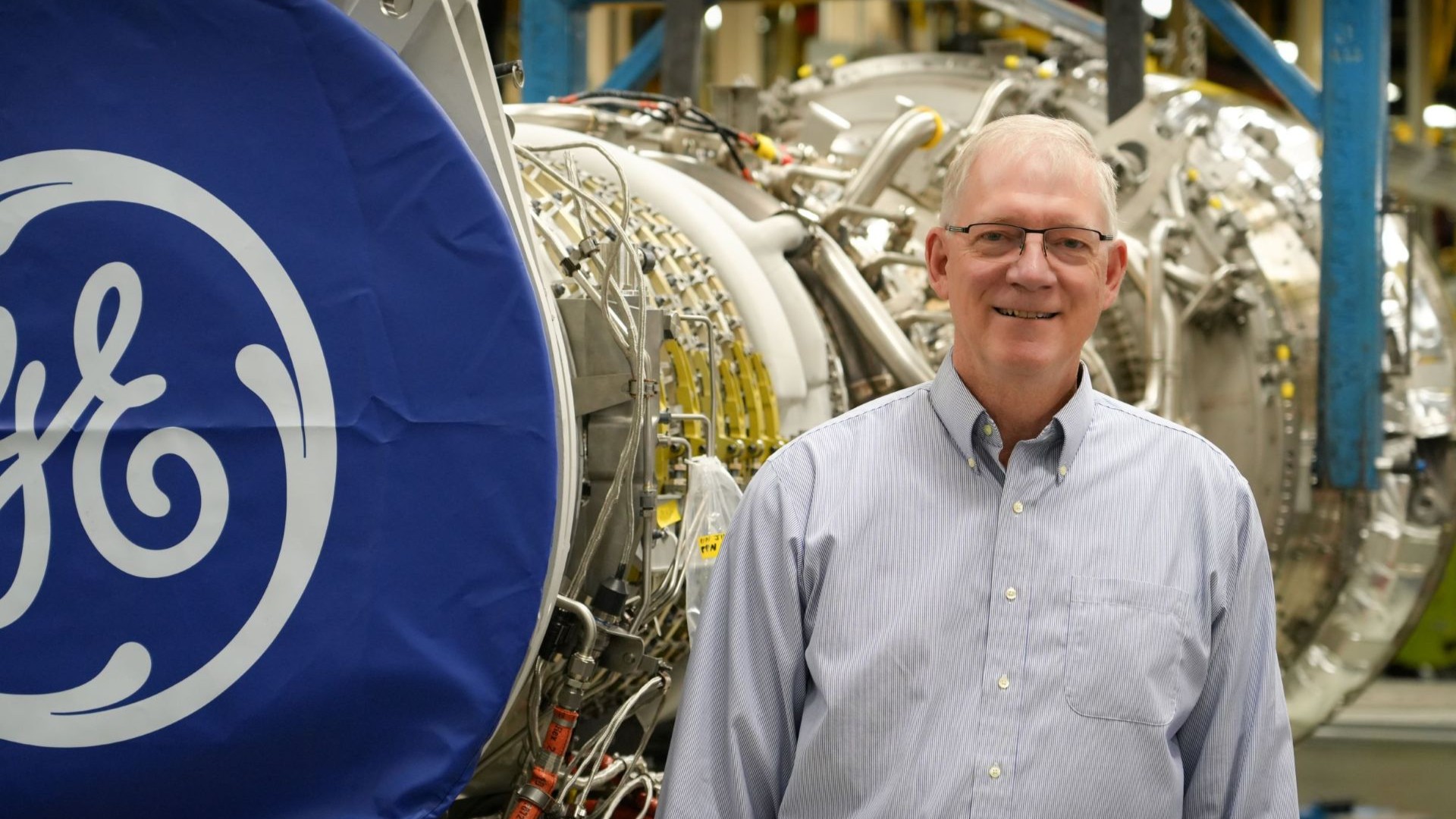 Steve Maynard standing in a button-up next to a GE monogram